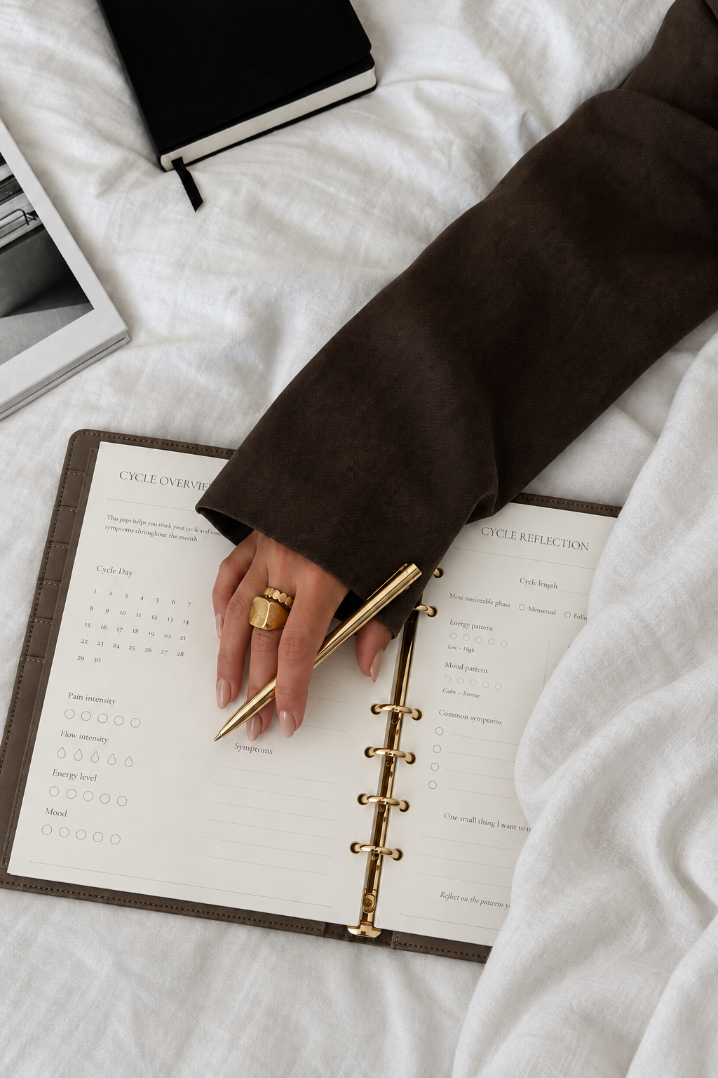 The Cycle Sync Planner with cycle overview and reflection inserts, hand and gold pen; editorial concept imagery
