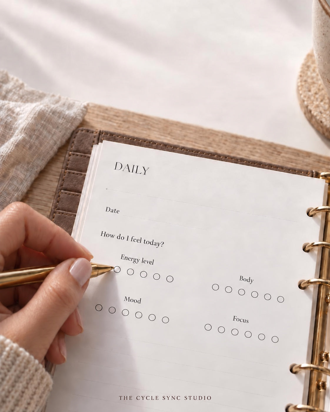 Daily check-in in The Cycle Sync Planner with a hand and gold pen